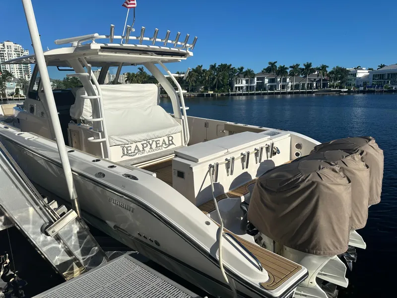 Slide: The Image of 2018 Pursuit 408S boat docked by waterfront homes under clear blue sky. - 6
