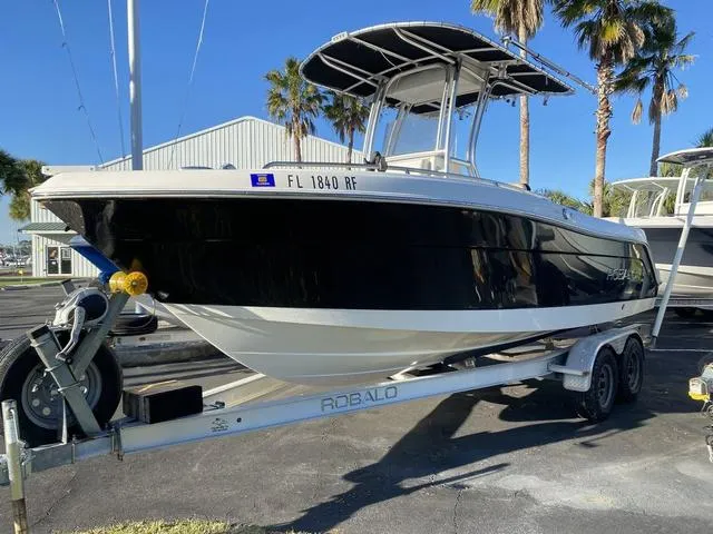 Slide: The Image of 2016 Robalo R222 boat on trailer, parked outdoors with palm trees in background. - 30