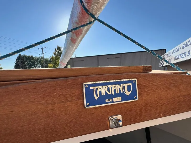 Slide: The Image of 2025 Tartan Fantail sailboat with wooden finish and branded nameplate under clear blue sky. - 13