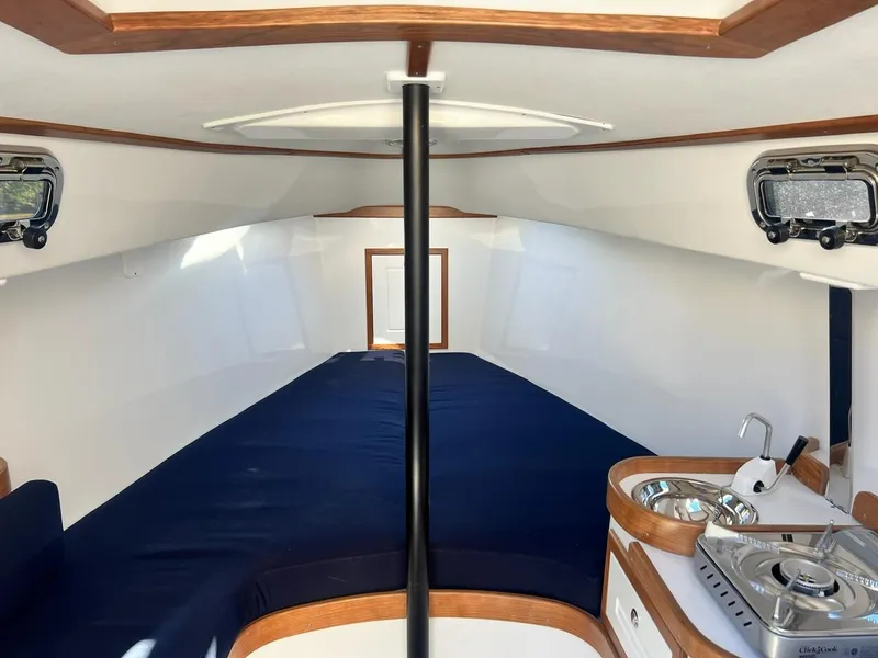 Slide: The Image of Interior of 2025 Tartan Fantail sailboat with blue seating and compact kitchen area. - 17