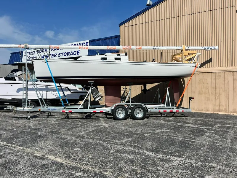 Slide: The Image of 2025 Tartan Fantail sailboat on trailer, parked outside storage facility. - 2