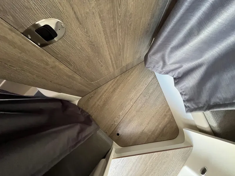 Slide: The Image of 2025 Bayliner Trophy T25 Explorer interior with wood finish and curtains. - 24