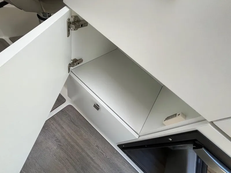 Slide: The Image of 2025 Bayliner Trophy T25 Explorer interior storage compartment with open cabinet door. - 31