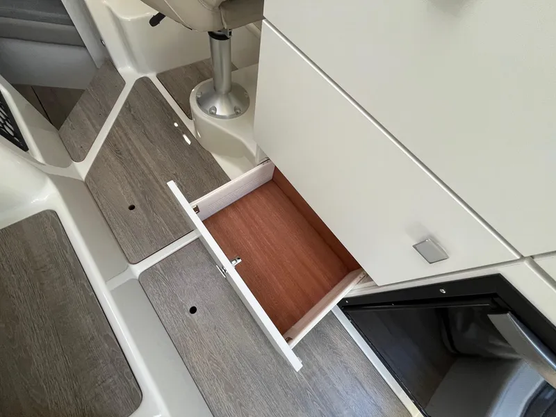 Slide: The Image of 2025 Bayliner Trophy T25 Explorer interior with open storage drawer and wood flooring. - 32