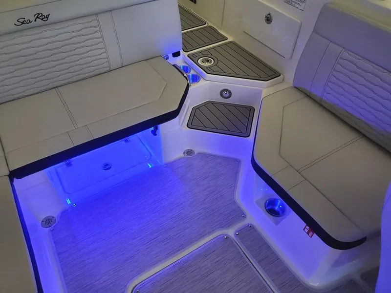 Slide: The Image of 2025 Sea Ray SPX 230 boat interior with blue LED lighting and cushioned seating. - 31