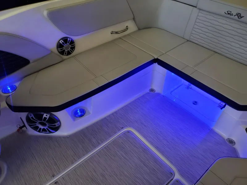 Slide: The Image of Interior of 2025 Sea Ray SPX 230 boat with blue LED lighting and cushioned seating. - 32