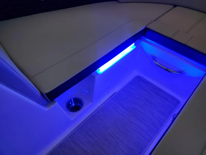 Slide: The Image of 2025 Sea Ray SPX 230 boat interior with blue LED lighting and seating area. - 34