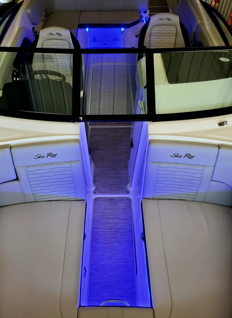 Slide: The Image of 2025 Sea Ray SPX 230 boat interior with blue LED lighting and cushioned seating. - 35