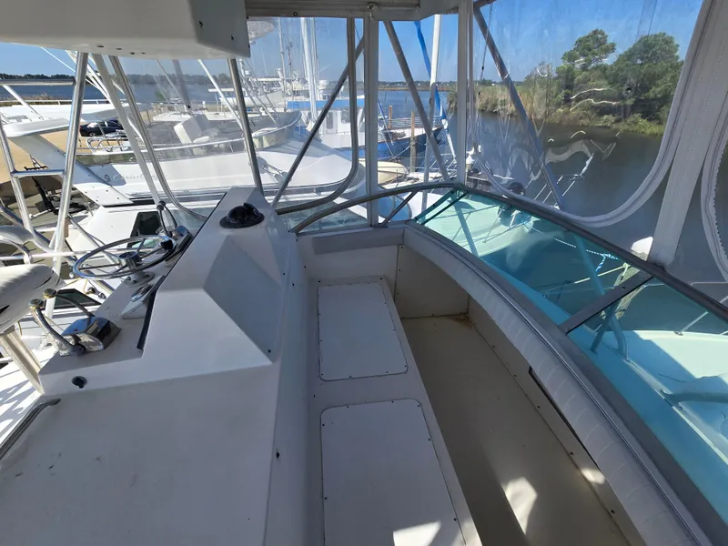 Slide: The Image of 1981 Bertram Convertible boat interior with helm, overlooking marina and waterway. - 13