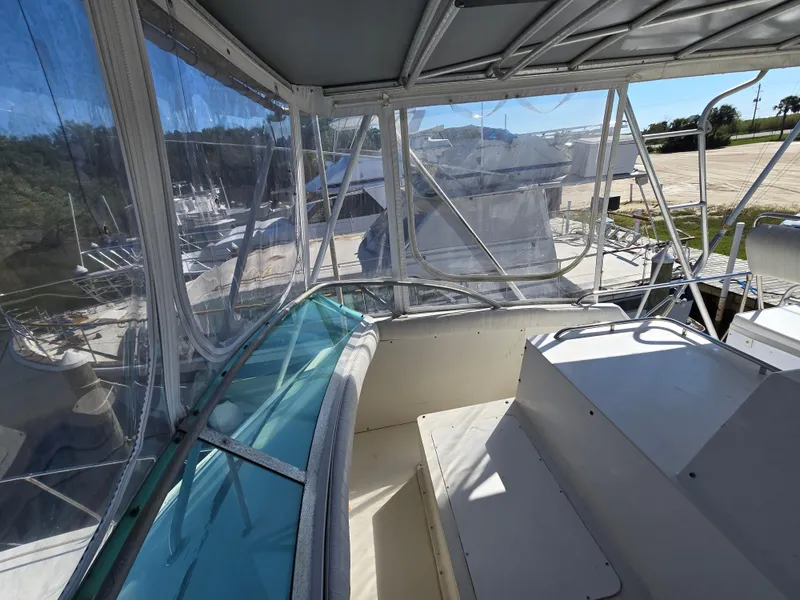 Slide: The Image of 1981 Bertram Convertible boat interior with clear enclosure and seating area. - 14