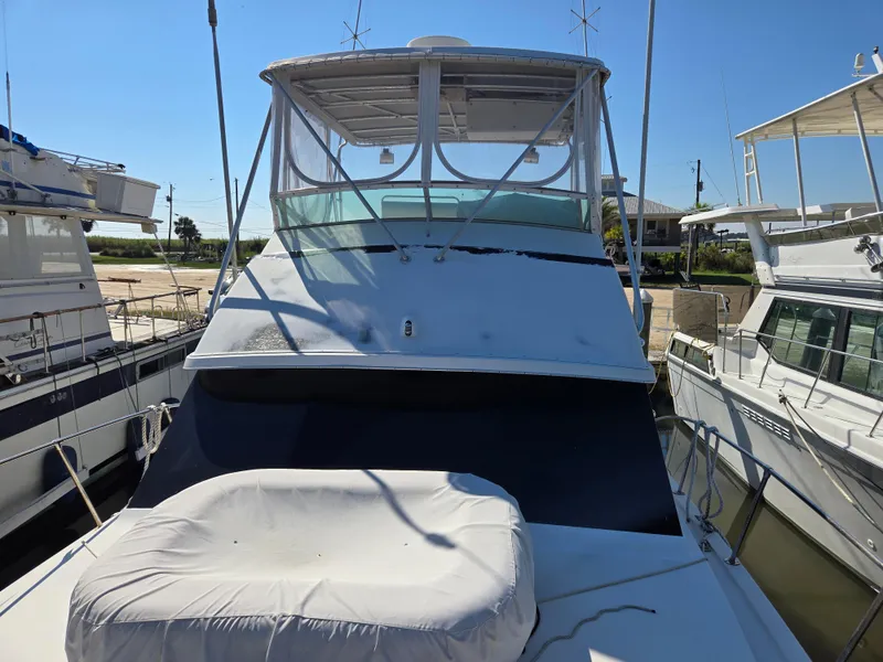 Slide: The Image of 1981 Bertram Convertible yacht docked, featuring a covered seating area and sleek design. - 15