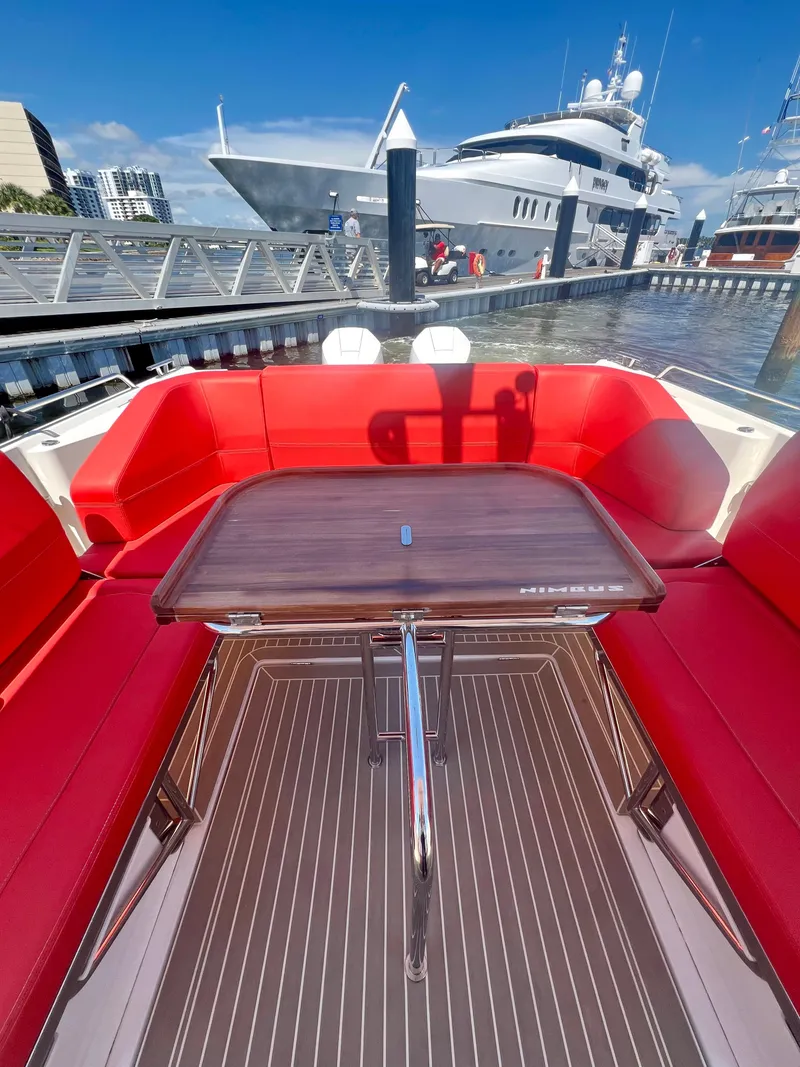 Slide: The Image of Nimbus T11 #98 TRADE! 2022 boat with red seating and wooden table at marina. - 18