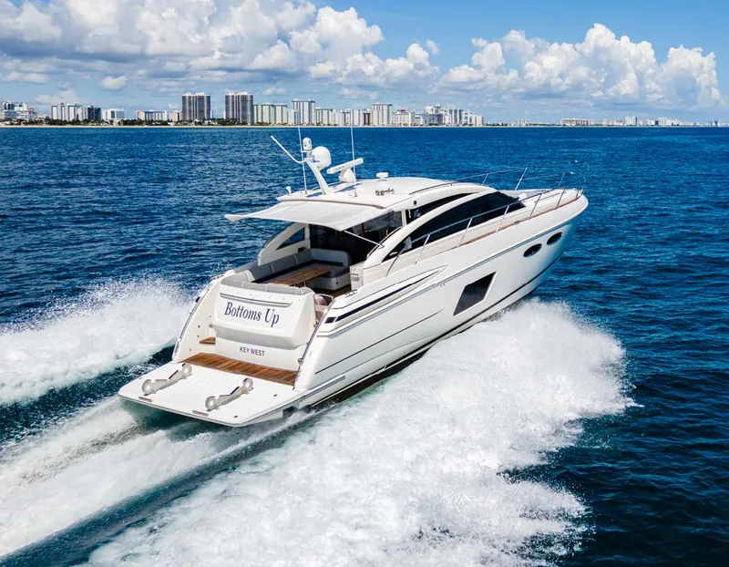 Slide: The Image of 2015 Princess V52 yacht cruising on open water with city skyline in background. - 29