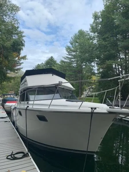 Slide: The Image of 1985 Carver 3227 Convertible boat docked by a wooded lakeside. - 4