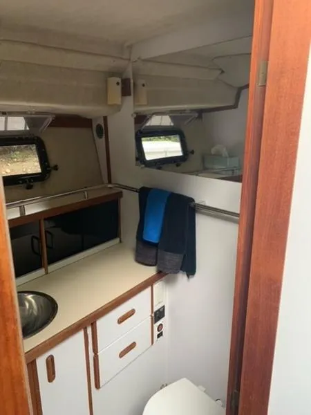 Slide: The Image of 1985 Carver 3227 Convertible boat bathroom with sink, storage, and portholes. - 7