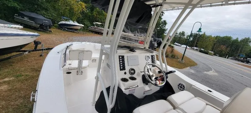 Slide: The Image of 2021 Robalo R200 boat interior with steering console and seating, parked outdoors. - 10
