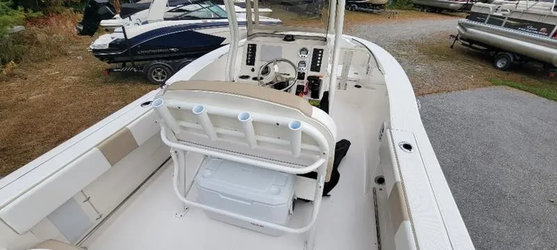 Slide: The Image of 2021 Robalo R200 boat interior with seating and console, parked on gravel. - 15