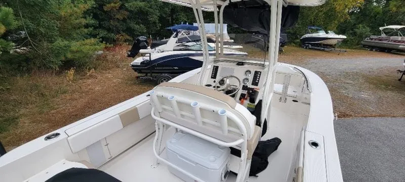 Slide: The Image of 2021 Robalo R200 boat with center console, parked outdoors among trees and other boats. - 5