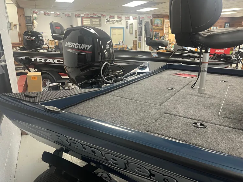 Slide: The Image of 2025 Ranger RT178 boat with Mercury engine in showroom, featuring carpeted deck and seating. - 3