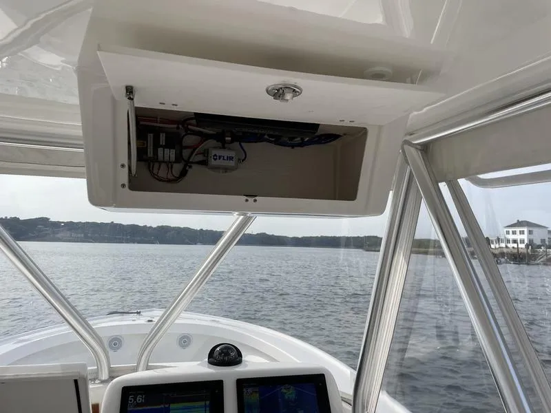 Slide: The Image of 2016 Jarrett Bay 32 Walk Around boat interior with navigation equipment on a calm waterway. - 6