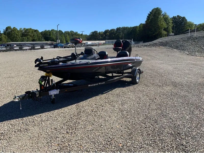 Slide: The Image of 2025 Ranger Z185 boat on gravel lot, surrounded by trees and clear blue sky. - 7