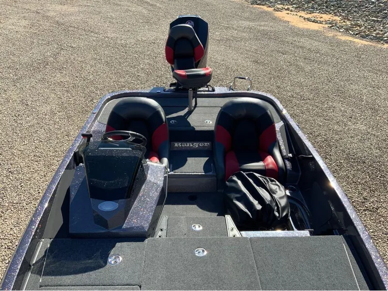 Slide: The Image of 2025 Ranger Z185 boat interior with black and red seats on gravel surface. - 8
