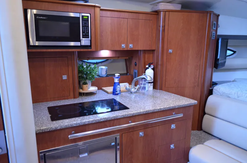 Slide: The Image of 2009 Monterey 320 Sport Yacht interior kitchen with microwave, stove, and wooden cabinetry. - 24