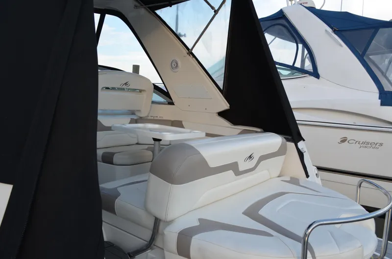 Slide: The Image of 2009 Monterey 320 Sport Yacht interior with white seating and table, docked beside another yacht. - 6