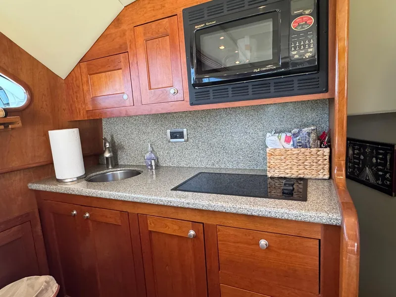 Slide: The Image of 2003 Rampage 45 Convertible yacht kitchen with microwave, sink, and wooden cabinets. - 14