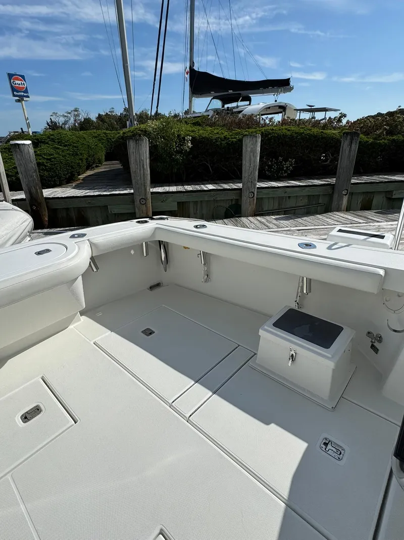 Slide: The Image of 2003 Rampage 45 Convertible boat deck with seating and storage, docked under clear blue sky. - 34