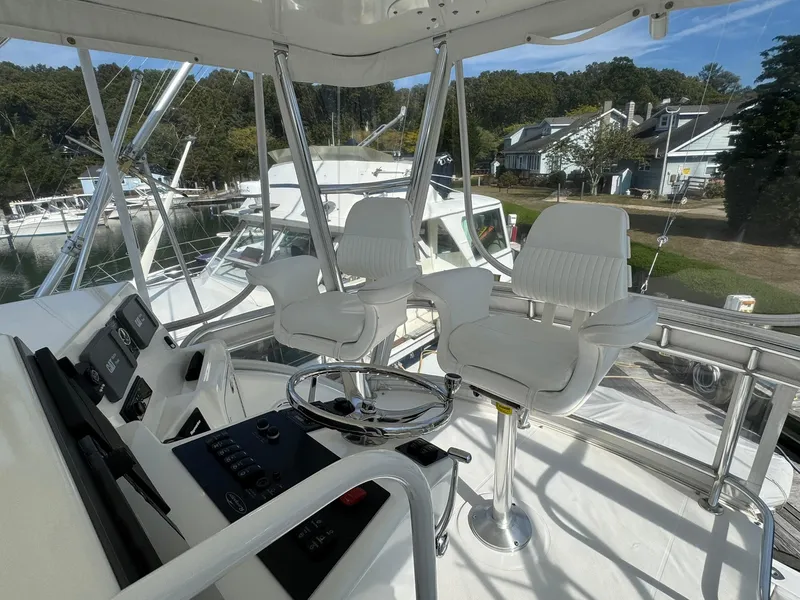 Slide: The Image of 2003 Rampage 45 Convertible yacht helm with dual white captain chairs and control panel. - 36