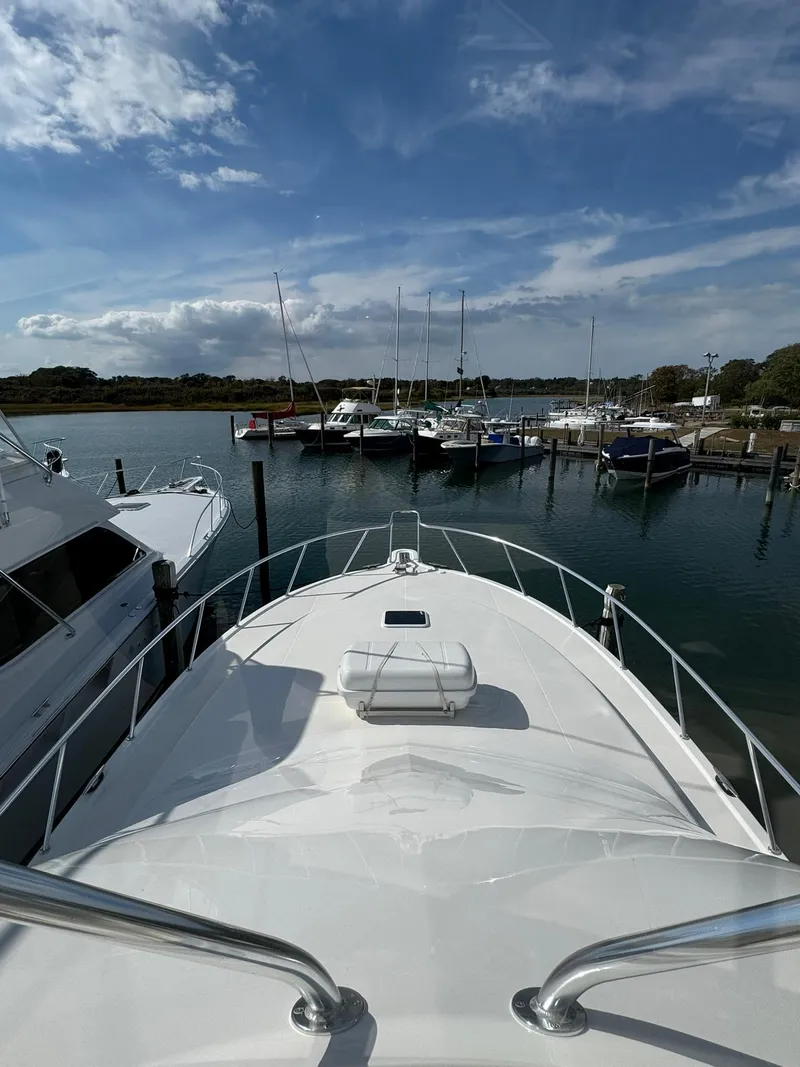 Slide: The Image of 2003 Rampage 45 Convertible yacht docked at a marina under a partly cloudy sky. - 43