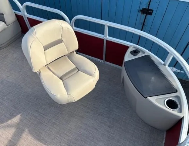 Slide: The Image of 2023 Sun Tracker Bass Buggy 18 DLX boat seat and console, beige upholstery, blue background. - 10