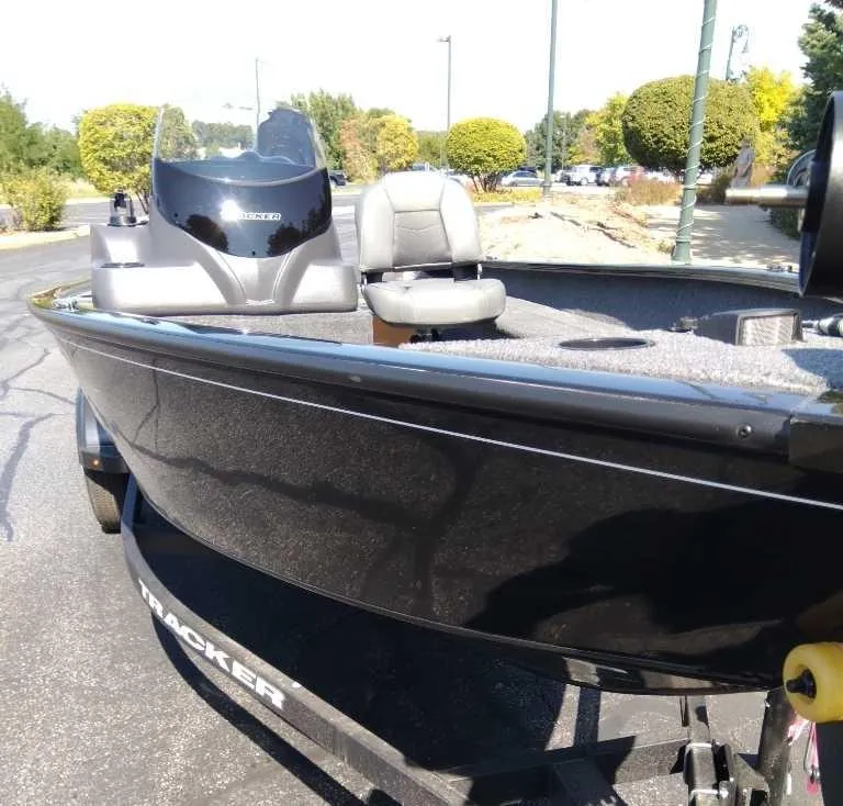 Slide: The Image of 2025 Tracker Pro Guide V-16 SC boat, sleek black design, parked outdoors. - 2