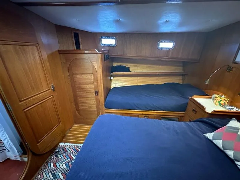 Slide: The Image of Cozy 1986 C. Raymond Hunt Design yacht cabin with wooden interior and twin beds. - 24