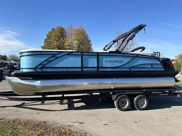 The Image of 2025 Godfrey Monaco 235SB pontoon boat on calm lake waters. - 1