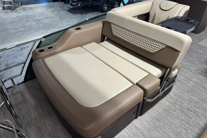 Slide: The Image of 2025 Godfrey Monaco 235 SFL boat lounge with beige and brown seating, cup holders, and flip lounge feature. - 11