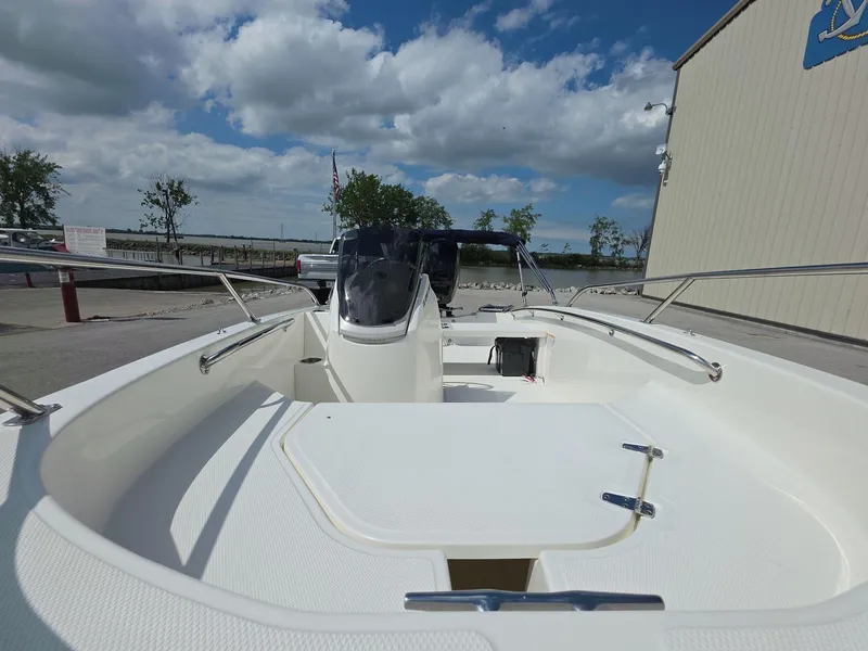 Slide: The Image of 2025 Boston Whaler 130 Super Sport boat docked under a partly cloudy sky. - 7