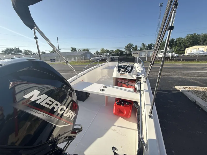 Slide: The Image of 2025 Boston Whaler 130 Super Sport boat with Mercury engine, docked outdoors. - 5