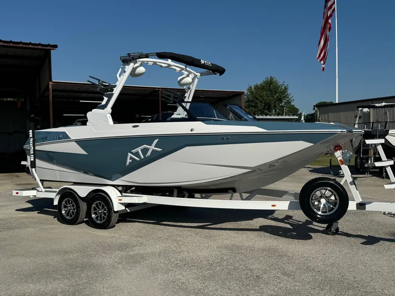 The Image of 2025 ATX Surf Boats 22 Type-S on trailer, parked outdoors with American flag in background. - 0
