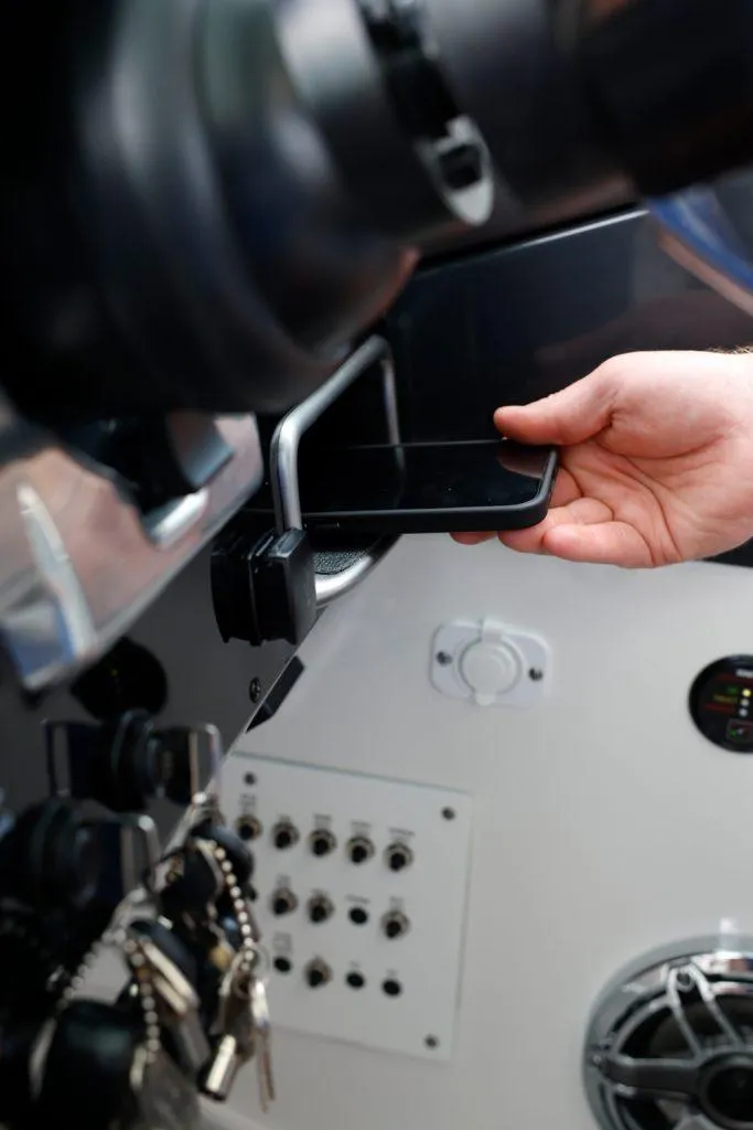 Slide: The Image of Hand placing phone in holder on 2025 Formula 330 CBR dashboard. - 23