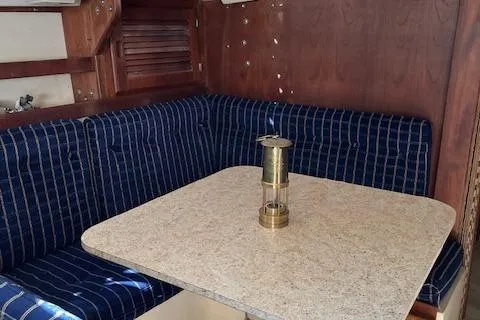 Slide: The Image of Interior of 1985 Catalina 30 sailboat with blue-striped seating and a table. - 5