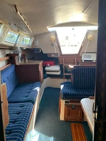 Slide: The Image of Interior of a 1985 Catalina 30 sailboat with blue-striped seating and wooden cabinetry. - 7