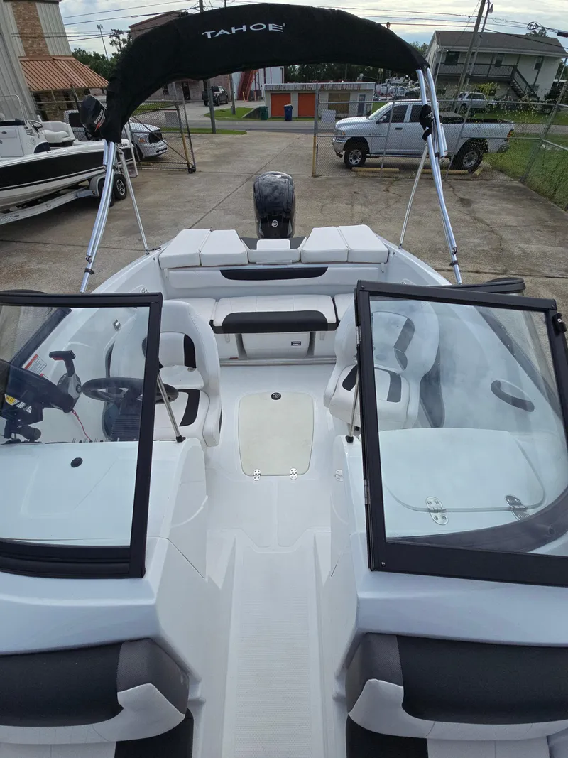 Slide: The Image of 2021 Tahoe 450 TF boat with open deck and seating, parked on concrete. - 10