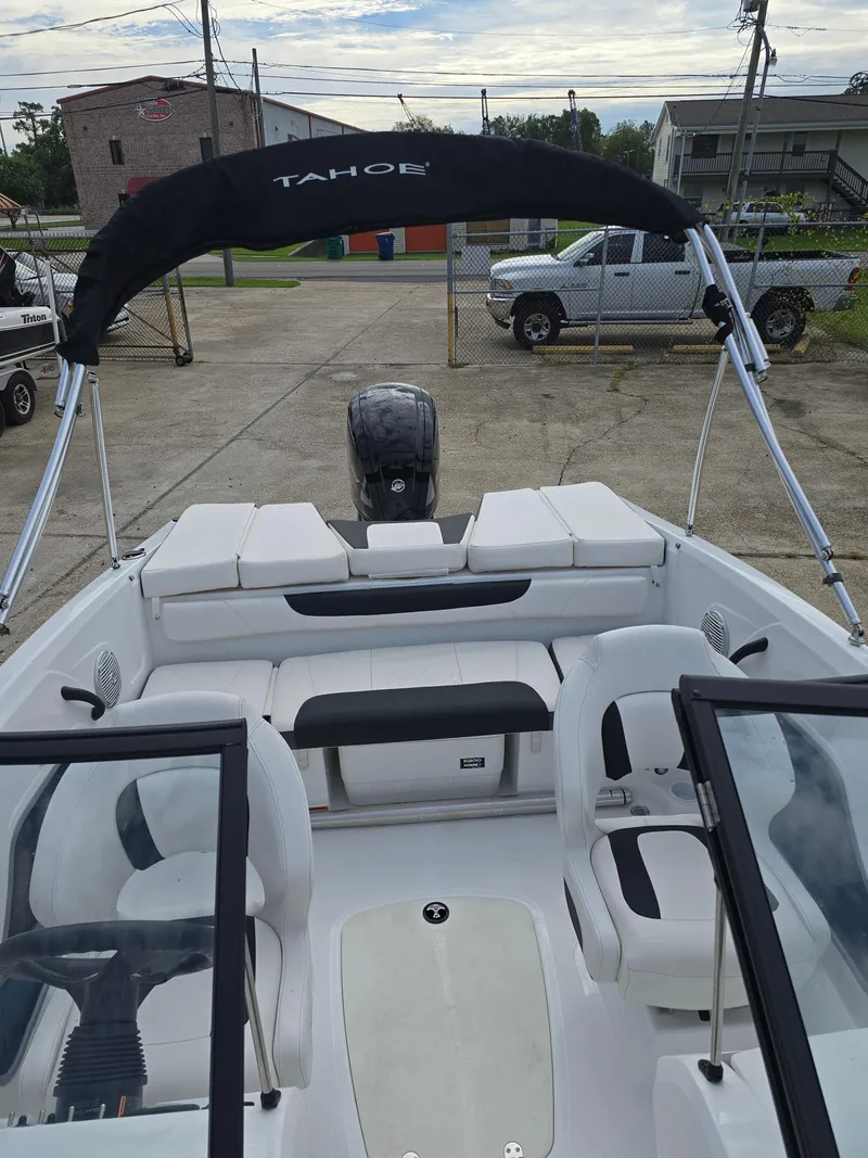 Slide: The Image of 2021 Tahoe 450 TF boat with seating and canopy, parked on concrete. - 18