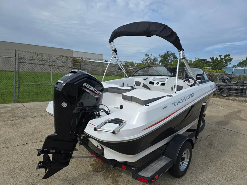 Slide: The Image of 2021 Tahoe 450 TF boat with Mercury engine on trailer, parked outdoors. - 2