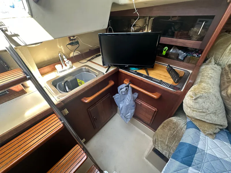 Slide: The Image of 1983 O'Day 28 sailboat interior with sink, TV, and wooden cabinetry. - 15