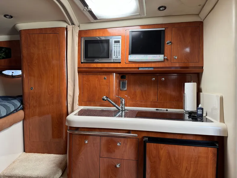 Slide: The Image of 2007 Four Winns 318 Vista yacht interior with kitchenette, microwave, and wood cabinetry. - 16