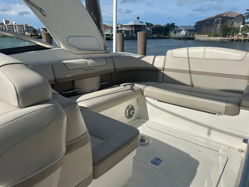 Slide: The Image of 2015 Formula 310 Bowrider interior with beige seating, docked by waterfront homes. - 5