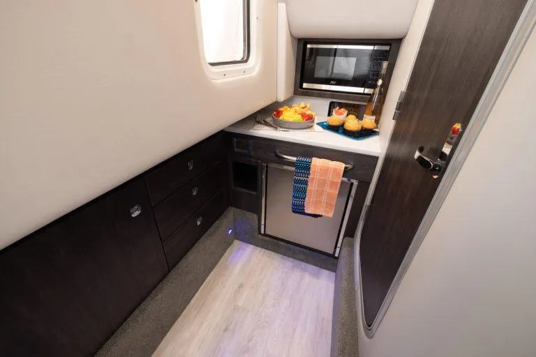Slide: The Image of 2025 Formula 350 CBR cabin kitchen with microwave, fridge, and snacks on counter. - 44